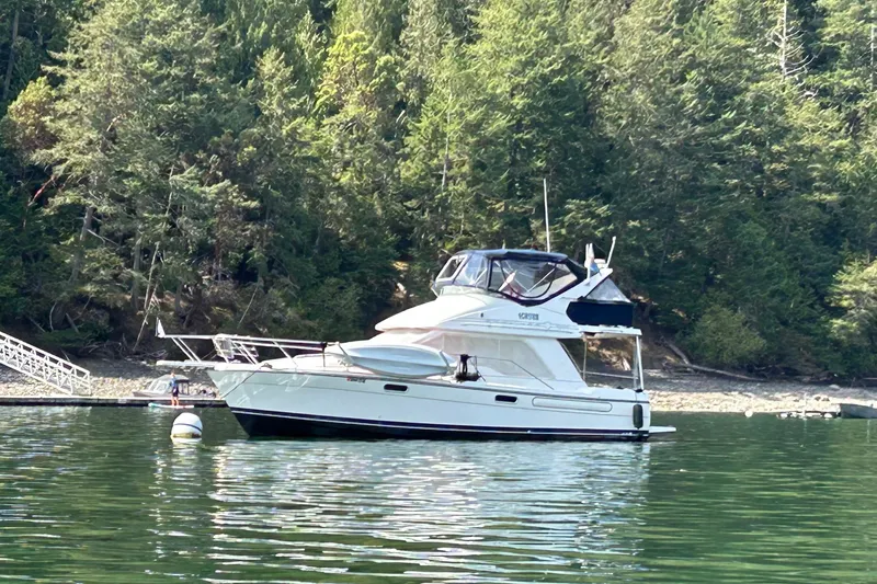 Slide: The Image of 2001 Bayliner 3388 Command Bridge Motoryacht on serene water near forested shoreline. - 1