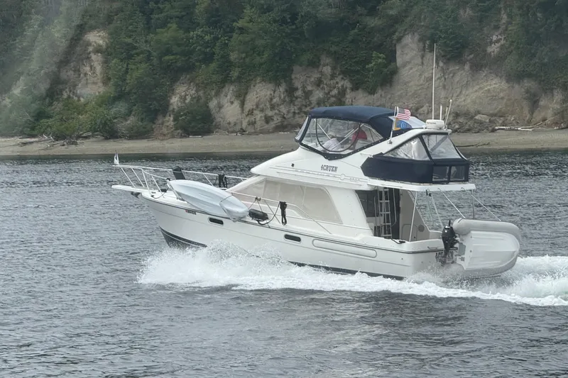 Slide: The Image of 2001 Bayliner 3388 Command Bridge Motoryacht cruising near a forested shoreline. - 3