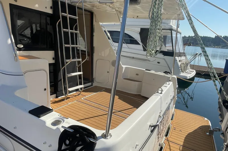 Slide: The Image of 2001 Bayliner 3388 Command Bridge Motoryacht docked, featuring spacious deck and ladder access. - 6