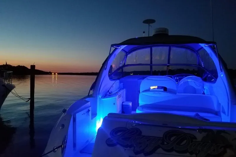 Slide: The Image of 2002 Sea Ray 360 Sundancer with blue interior lights at sunset on calm water. - 33
