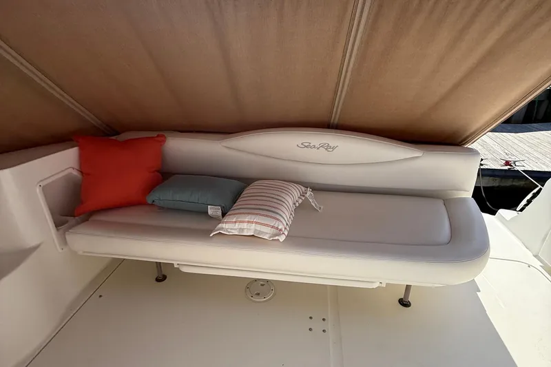 Slide: The Image of 2002 Sea Ray 360 Sundancer boat interior with cushioned seating and colorful pillows. - 9