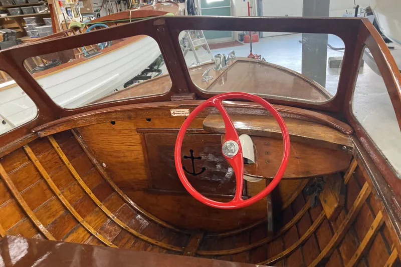 Slide: The Image of 1954 Lyman outboard boat interior with red steering wheel and wooden dashboard. - 2