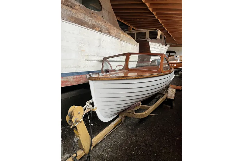 Slide: The Image of 1954 Lyman outboard boat on trailer in storage, showcasing classic wooden design. - 5
