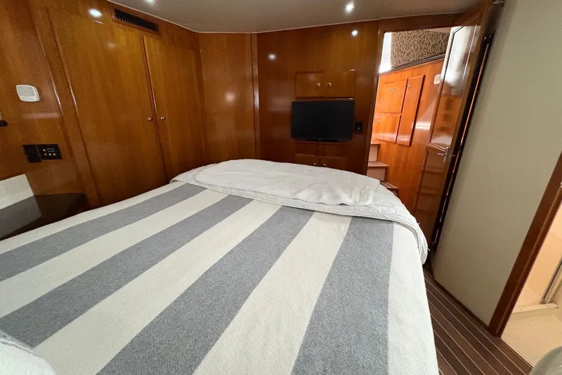 Slide: The Image of Cozy bedroom in 2002 Carver 406 Aft Cabin Motor Yacht with striped bedding and wood paneling. - 25