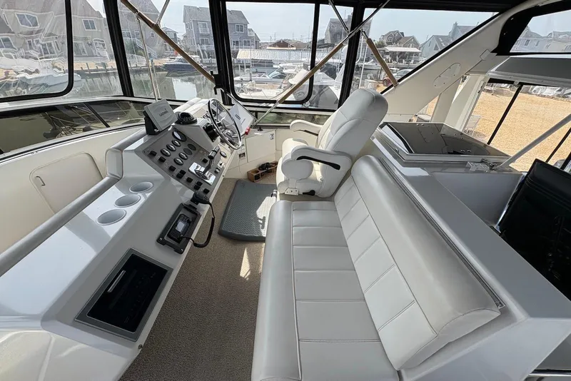 Slide: The Image of 2002 Carver 406 Aft Cabin Motor Yacht helm with white seating and control panel. - 10