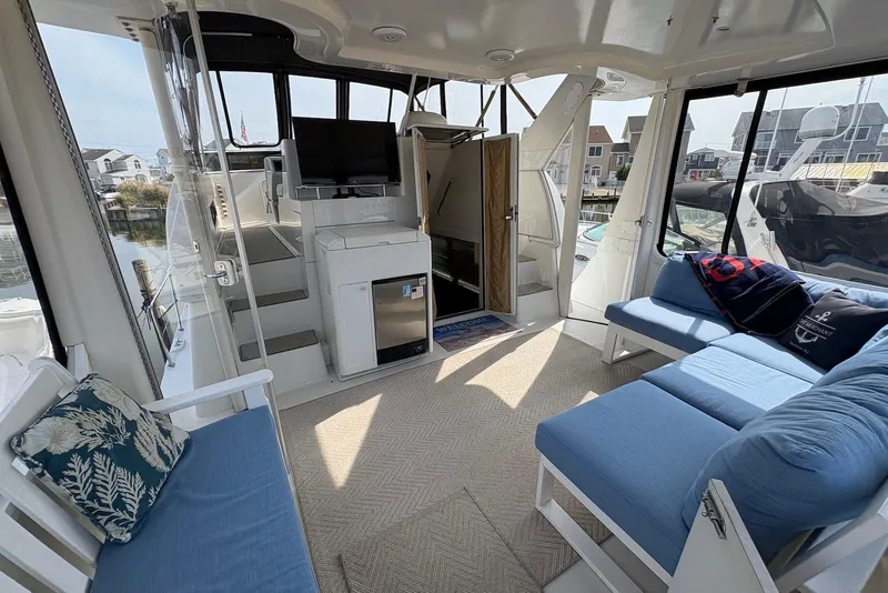 Slide: The Image of 2002 Carver 406 Aft Cabin Motor Yacht interior with seating, TV, and marina view. - 3