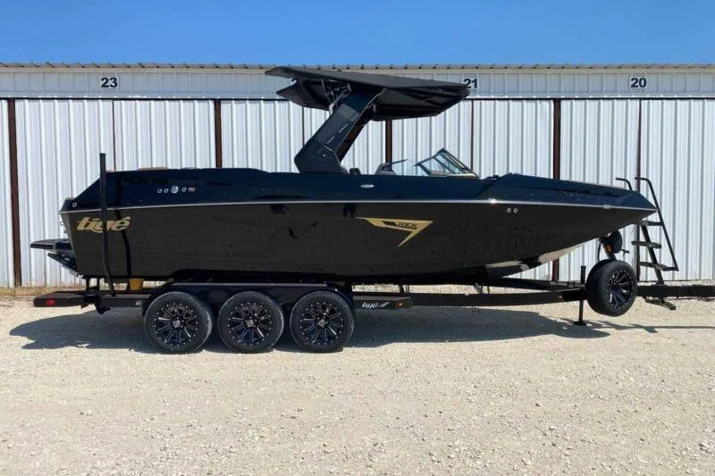 Slide: The Image of 2026 Tigé 24RZX boat on trailer, sleek black design, parked outdoors. - 0