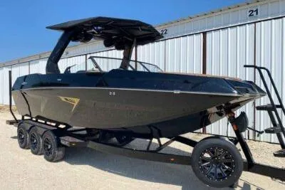 Slide: The Image of 2026 Tigé 24RZX boat on trailer, sleek black design, parked outdoors. - 1