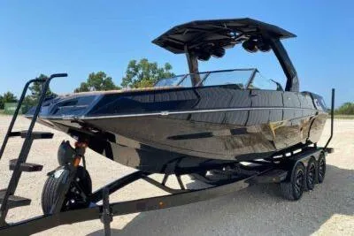 Slide: The Image of 2026 Tigé 24RZX boat on trailer, sleek black design, outdoor setting. - 2