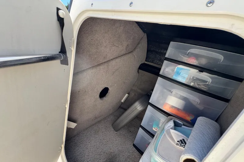 Slide: The Image of Storage compartment in a 2021 Stingray 231 DC boat with organized plastic drawers. - 12