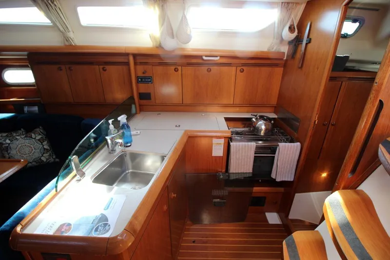 Slide: The Image of 2005 Jeanneau Sun Odyssey 40.3 yacht interior with wooden cabinetry and compact kitchen area. - 26