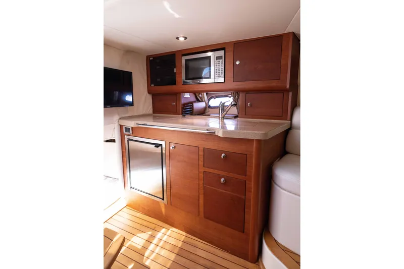 Slide: The Image of 2007 Chris Craft Corsair interior kitchen with wood cabinetry, microwave, and compact fridge. - 12