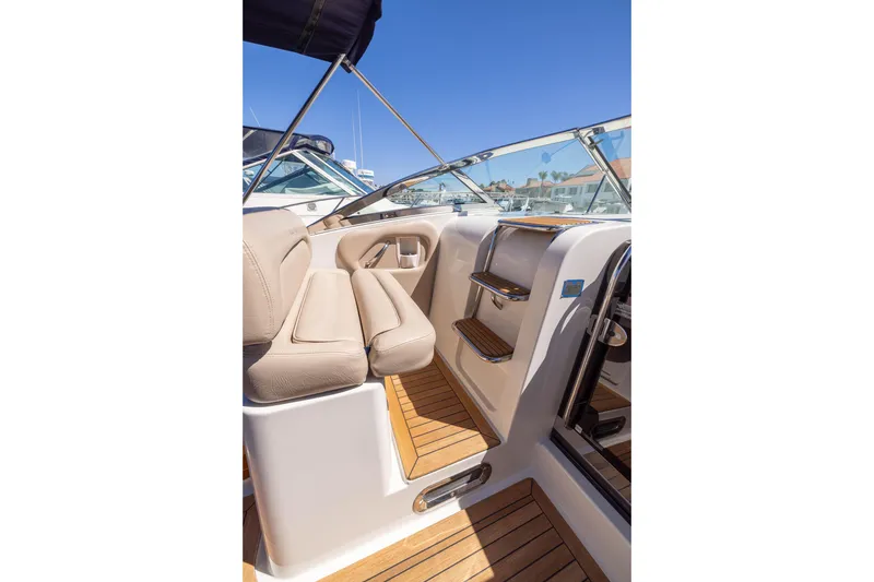 Slide: The Image of 2007 Chris Craft Corsair interior with beige seating and wooden flooring, under clear blue sky. - 8