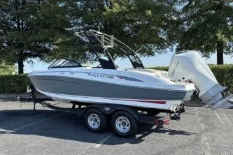 The Image of 2023 Tahoe 210 S boat on trailer, parked outdoors with trees in background. - 0