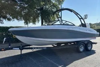 Slide: The Image of 2023 Tahoe 210 S boat on trailer, parked outdoors under trees. - 2