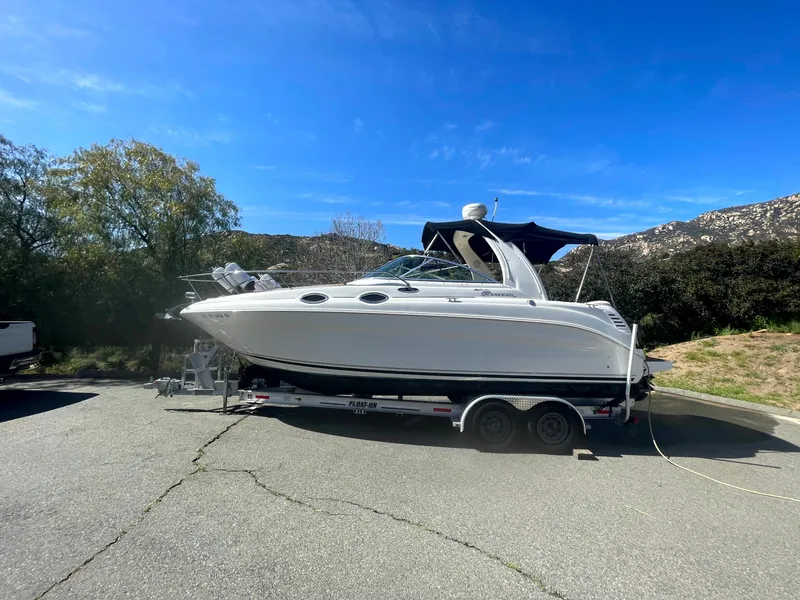 Slide: The Image of 2004 Sea Ray 260 Sundancer boat on trailer, parked outdoors under clear blue sky. - 1
