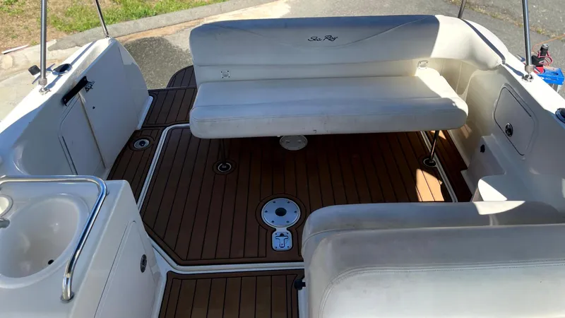 Slide: The Image of 2004 Sea Ray 260 Sundancer boat interior with white seating and wooden deck. - 11