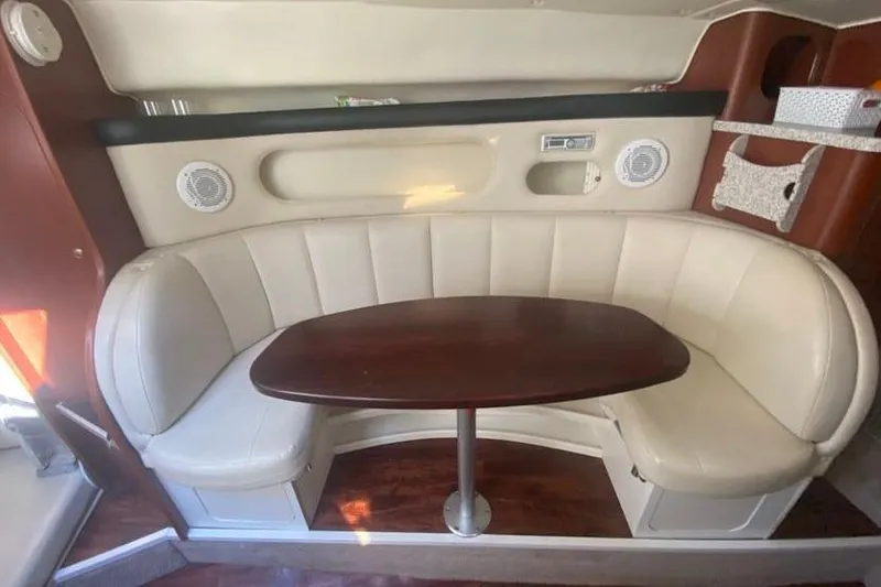 Slide: The Image of 2001 Rinker 310 Fiesta Vee interior with curved seating and wooden table. - 12