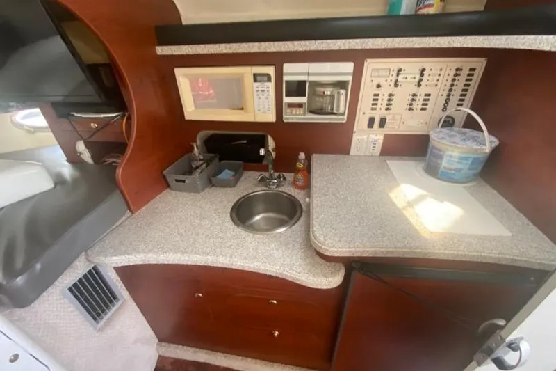 Slide: The Image of 2001 Rinker 310 Fiesta Vee boat interior with kitchenette, sink, and control panel. - 13