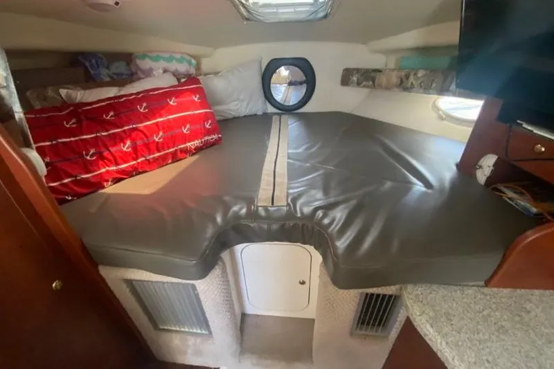 Slide: The Image of 2001 Rinker 310 Fiesta Vee cabin interior with bed, porthole, and storage. - 14