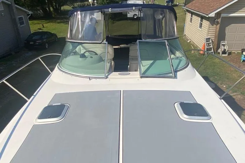 Slide: The Image of 2001 Rinker 310 Fiesta Vee boat with open deck and windshield, parked near houses. - 17