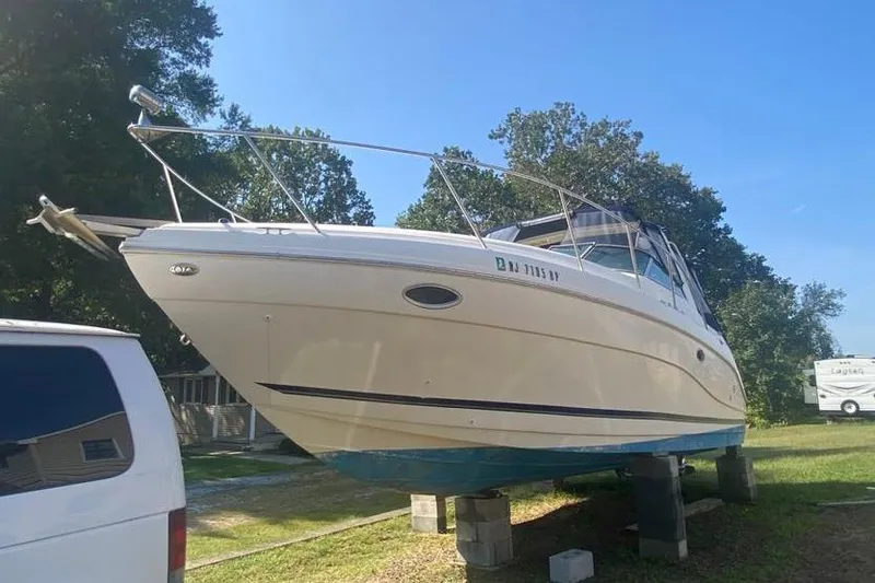 Slide: The Image of 2001 Rinker 310 Fiesta Vee boat on blocks, parked outdoors under clear sky. - 3