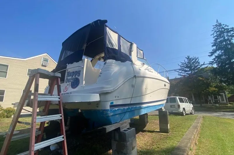 Slide: The Image of 2001 Rinker 310 Fiesta Vee boat on blocks, with a ladder and van nearby. - 5