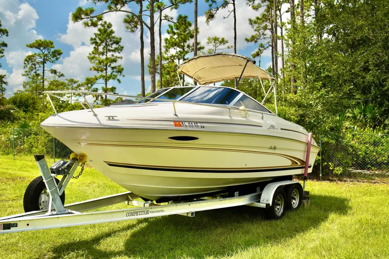 Slide: The Image of 2001 Sea Ray 215 Express Cruiser on trailer, parked on grass, with trees in background. - 1