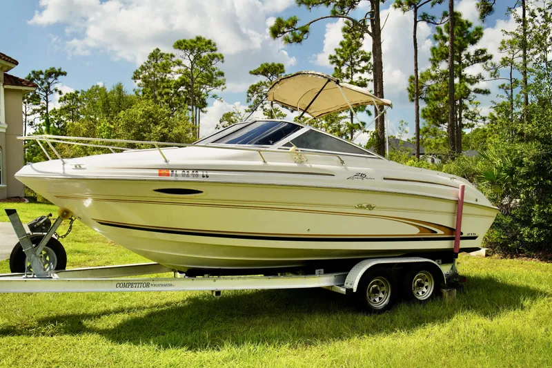 Slide: The Image of 2001 Sea Ray 215 Express Cruiser on trailer, surrounded by lush greenery. - 2