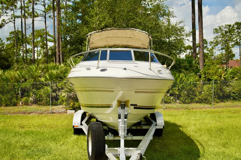 Slide: The Image of 2001 Sea Ray 215 Express Cruiser on trailer, parked on grass with trees in background. - 3