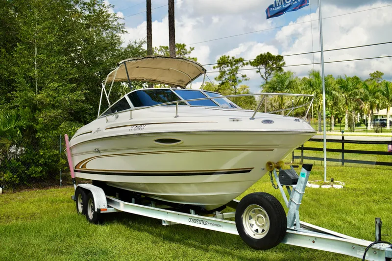 Slide: The Image of 2001 Sea Ray 215 Express Cruiser on trailer, parked on grass, under cloudy sky. - 4
