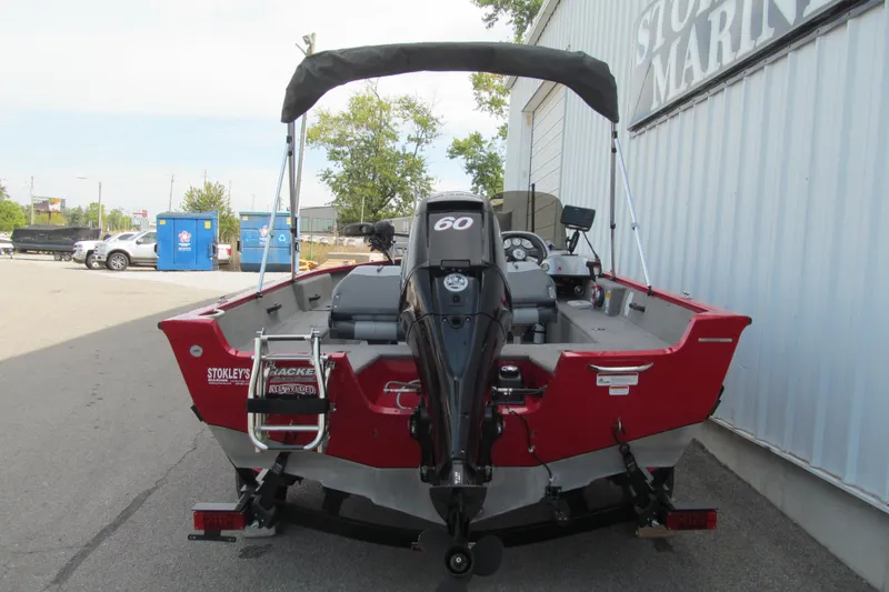 Slide: The Image of 2012 Tracker Pro Guide V-16 SC boat with outboard motor, parked near a marine shop. - 4