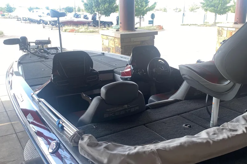 Slide: The Image of 2019 Skeeter ZX250 boat interior with seating and steering wheel, parked under a shelter. - 3