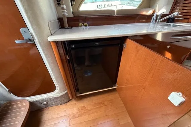 Slide: The Image of 2008 Sea Ray Sundancer 350 interior kitchen with wood cabinetry and compact refrigerator. - 36