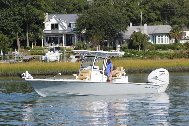 The Image of 2021 Sportsman Masters 267OE Bay Boat cruising on a calm river near waterfront homes. - 1