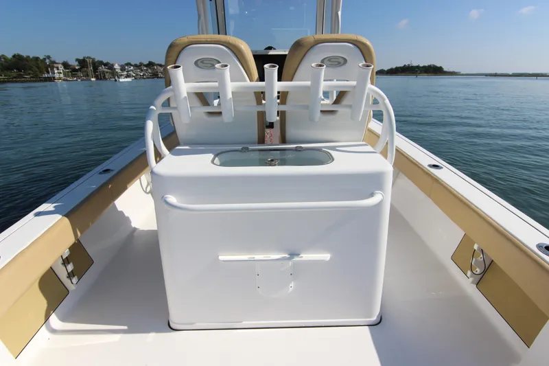 Slide: The Image of 2021 Sportsman Masters 267OE Bay Boat interior with rod holders and seating on calm water. - 18