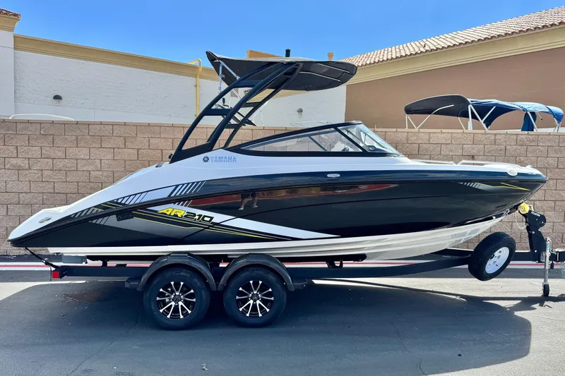 Slide: The Image of 2019 Yamaha AR210 boat on trailer, sleek black and white design, parked outdoors. - 0