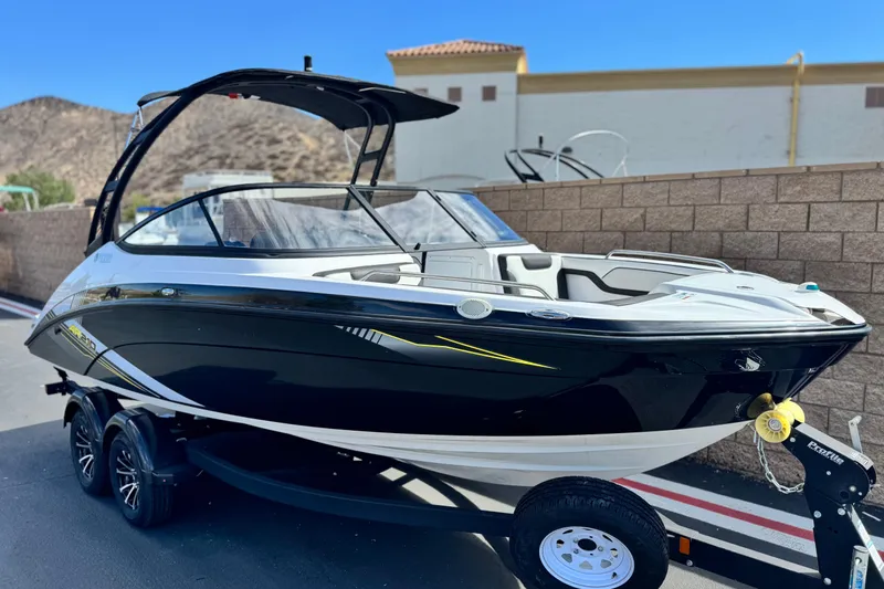 Slide: The Image of 2019 Yamaha Boats AR210 on trailer, sleek black and white design, parked outdoors. - 1