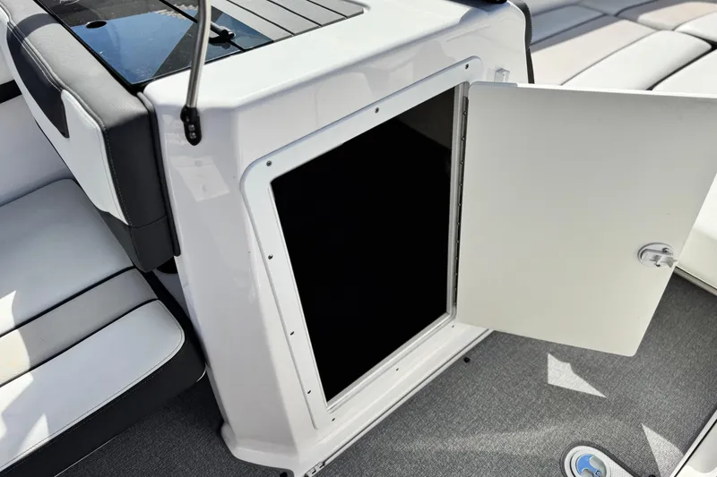 Slide: The Image of 2019 Yamaha AR210 boat interior storage compartment with open door, showcasing seating and flooring. - 22