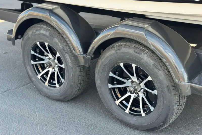 Slide: The Image of 2019 Yamaha Boats AR210 trailer wheels with sleek black rims and fenders. - 30