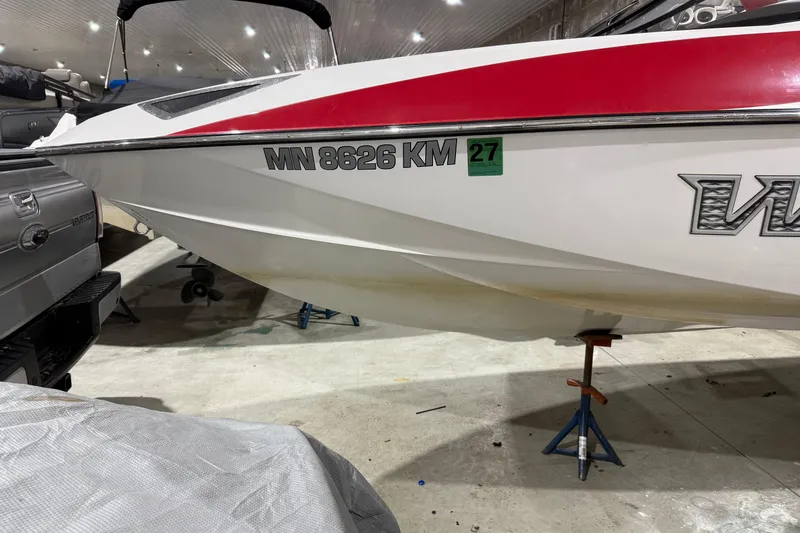 Slide: The Image of 2009 Malibu Wakesetter 23 LSV boat in storage, featuring red and white hull design. - 43