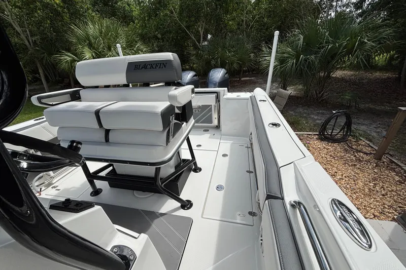 Slide: The Image of 2020 Blackfin 252 CC boat interior with seating and console, surrounded by lush greenery. - 20