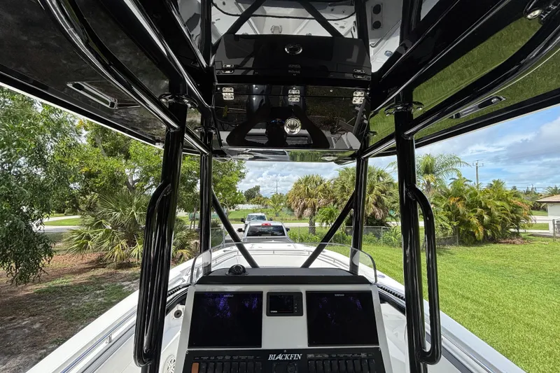 Slide: The Image of 2020 Blackfin 252 CC boat interior with console and lush greenery background. - 23