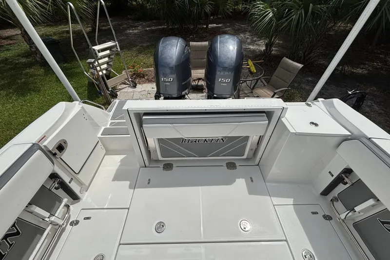 Slide: The Image of 2020 Blackfin 252 CC boat deck with twin 150 horsepower engines, surrounded by lush greenery. - 25