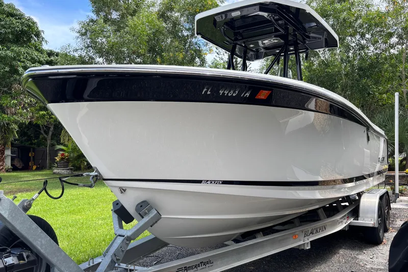 Slide: The Image of 2020 Blackfin 252 CC boat on trailer, parked outdoors with lush greenery. - 4