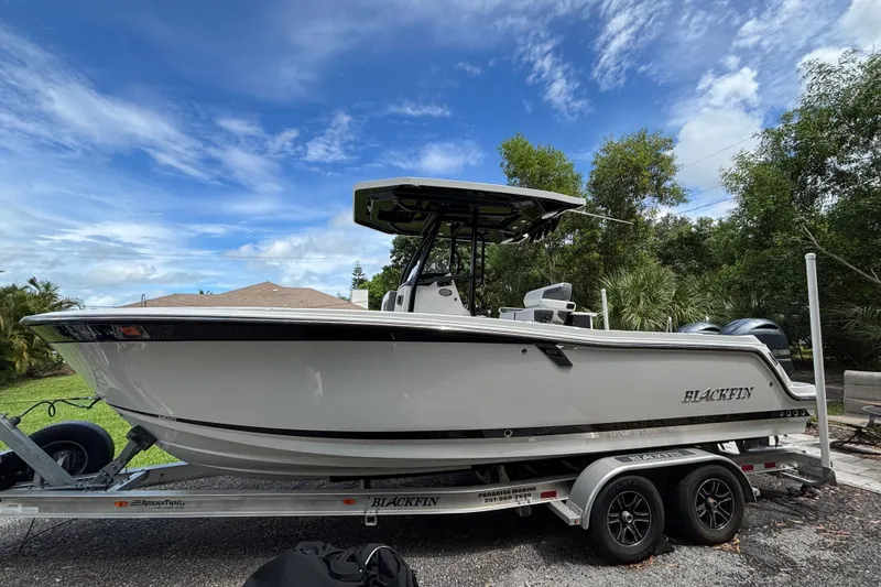 Slide: The Image of 2020 Blackfin 252 CC boat on trailer, parked outdoors under a blue sky. - 5