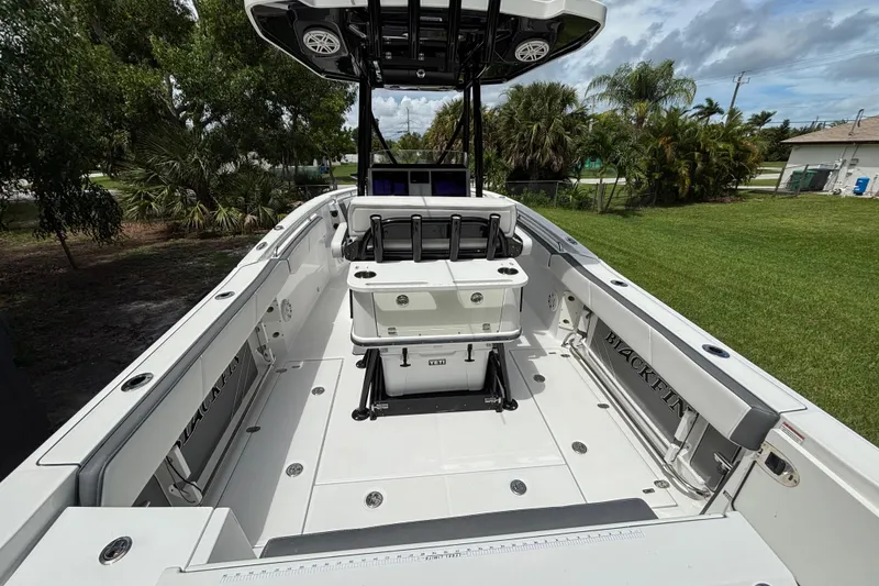 Slide: The Image of 2020 Blackfin 252 CC boat interior with seating and storage, surrounded by lush greenery. - 9