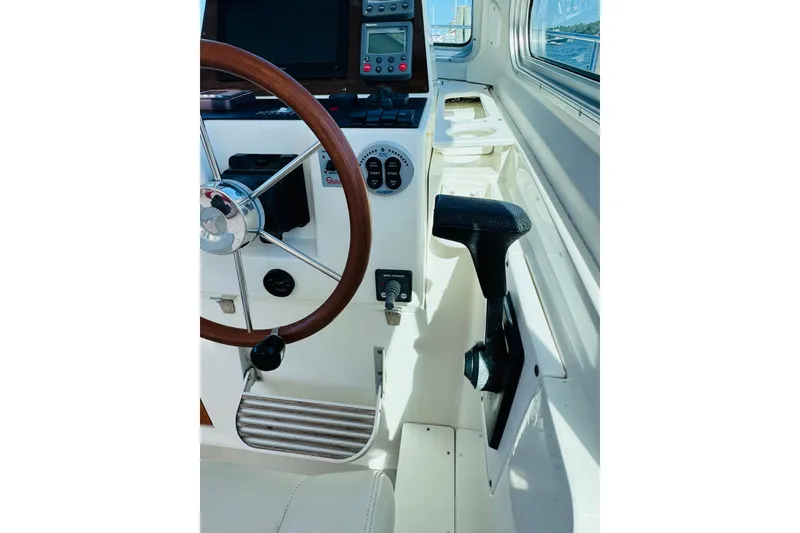 Slide: The Image of 2007 Back Cove 29 boat helm with wooden steering wheel and navigation controls. - 12