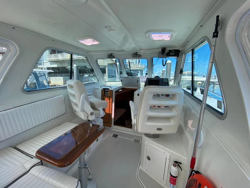 Slide: The Image of 2007 Back Cove 29 boat interior with white seating and wooden table. - 13