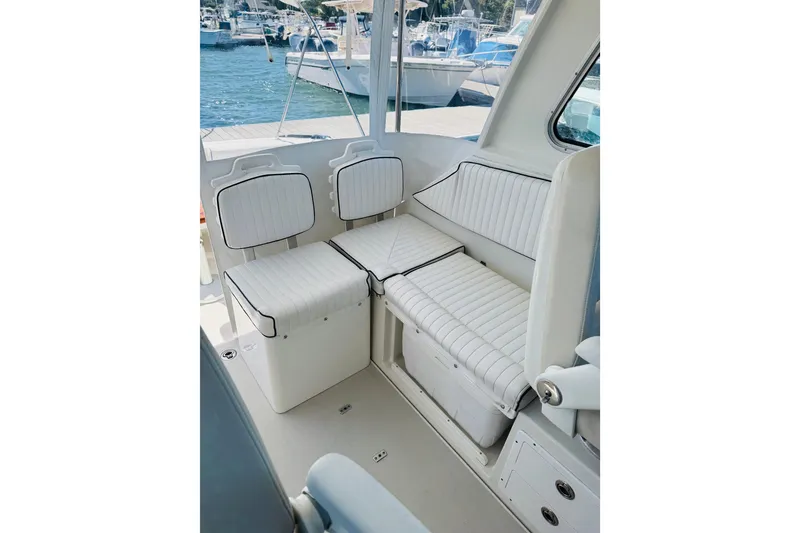 Slide: The Image of 2007 Back Cove 29 boat interior with white cushioned seating and marina view. - 16